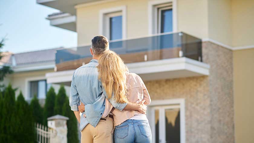 Bild mit einem Paar, das auf ihr Eigenheim schaut und darüber nachdenkt, ob die neue Grundsteuer alle Wohnungs- und Haus-Eigentümer betrifft